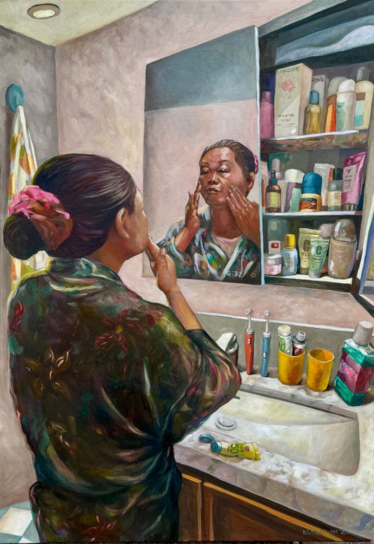 Oil painting of a woman in a floral robe applying skincare at a bathroom mirror beside a crowded cabinet – Kris Soguilon